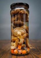 Pickled mushrooms in a glass jar . Salted homemade mushrooms . Rustic food . photo