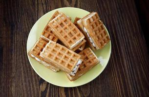 A pile of fresh Viennese waffles lie on a yellow plate. photo