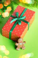 Red rectangular in polka dots wrapped box with gingerbread man on green backdrop with Xmas lights. photo