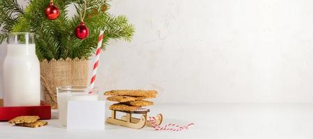 banner de vacaciones con leche tradicional para santa, galletas y ramas de abeto en blanco. copie el espacio foto