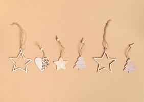 fila de decoraciones navideñas artesanales - estrellas de madera, árboles de navidad, corazones sobre fondo beige con espacio para copiar. foto