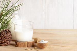 Organic milk replacer - cedar milk in glass, flour in wooden spoon for its cooking on wooden table. photo