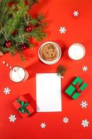 Christmas arrangement of milk glasses, cookies, white sheet, gift boxes, fir branches on red. photo