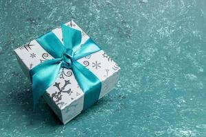 Patterned gift box with DIY bow on turquoise textured background. Christmas or New Year monochrome image. photo