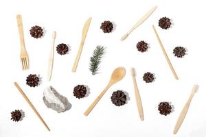 Christmas arrangement of eco-friendly bamboo toothbrushes, wooden cutlery, pine cones, fir twig and stone on white. photo