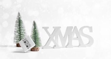 Xmas holiday background. Close up Christmas decorations white letters XMAS, Xmas trees, DIY gift box on white. photo
