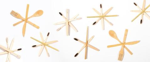 banner creativo de navidad - patrón de cepillos de dientes de bambú natural y cubiertos de madera dispuestos como copos de nieve en blanco. foto