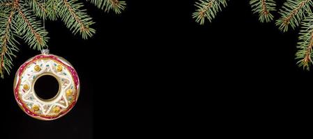 decoración de navidad donut de vidrio colorido y ramitas de abeto verde sobre negro. bandera. copie el espacio. Bosquejo. foto