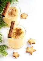 Traditional Christmas drink eggnog with cinnamon in two glasses, Xmas cookies stars on white. photo