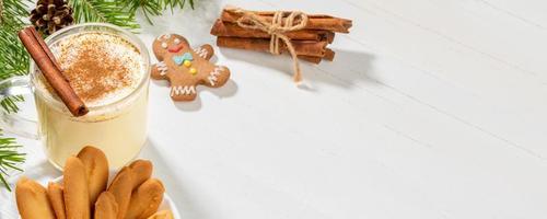 Christmas banner with eggnog with cinnamon and ginger cookies on white wooden backdrop. photo