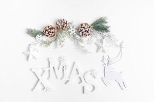 Festive composition with reusable Christmas decor - white letters, twigs, pine cones, deer, snowflakes, stars on white. photo