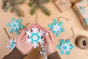 Step by step instruction of make DIY Xmas toy snowflake. Step 7 - Tie threads on snowflakes in knots. Flat lay. photo