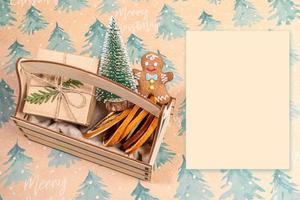 Wooden box with Christmas decorations and empty paper sheet on festive backdrop. Holiday mock up. photo