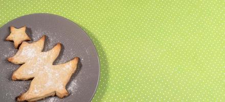 Festive banner with homemade baking as Christmas tree on grey plate on polka dots green backdrop. photo
