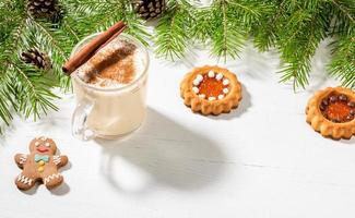 Xmas eggnog with cinnamon, ginger man, ginger cookies on white wooden backdrop with fir branches. photo