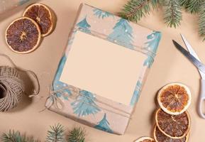 Christmas or New Year DIY wrapped in festive paper gift box with empty space on beige backdrop. photo