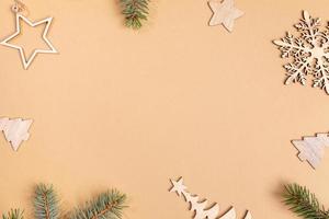 Christmas beige background with frame of wooden festive decorations - Xmas toys and fir tree twigs with copy space. photo