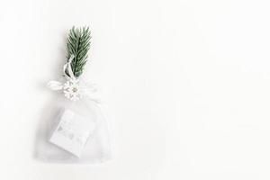 Xmas festive minimal backdrop with trendy Christmas small diy gift in mesh pouch and reusable decor on white backdrop. photo