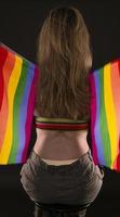 mujer lesbiana sosteniendo la bandera del arco iris aislada sobre fondo negro. símbolo internacional lgbt de la comunidad lesbiana, gay, bisexual y transgénero. foto