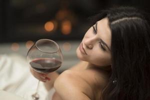 attractive brunette drinking wine by a fireplace photo