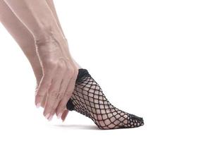 woman puts on fishnet stockings on white background photo