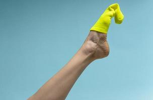 Woman with beautiful legs wears green socks on her feet. Isolated on blue background photo