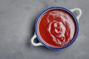 salsa de tomate, taza de cerámica sobre fondo blanco foto