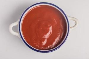 salsa de tomate, taza de cerámica sobre fondo blanco foto