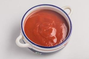 salsa de tomate, taza de cerámica sobre fondo blanco foto