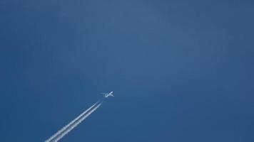 lungo sparo, passeggeri Jet aereo volante su alto altitudine su chiaro blu cielo in partenza bianca Fumo tracciare di scia di condensazione dietro. aria mezzi di trasporto concetto video