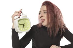 worried young woman holding alarm clock in her hand photo
