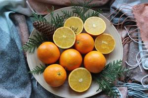 naranjas enteras y rodajas en un plato blanco foto