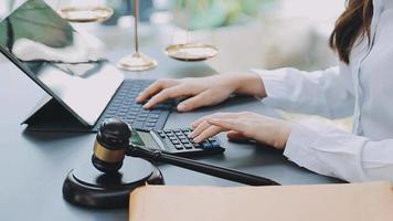 Justice and law concept.Male judge in a courtroom with the gavel, working with, computer and docking keyboard, eyeglasses, on table in morning light video