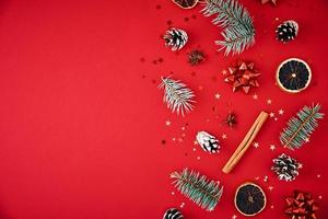 Fir branches, pine cones, dried fruits and festive confetti on a red background photo