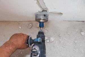 Builder with hummer drill perforator drills hole in a wall photo