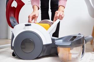 Woman takes out container of dust from vacuum cleaner photo