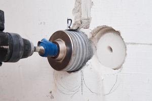 Builder with hummer drill perforator drills hole in a wall photo