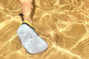 Legs in swim shoes under water with sun reflection photo