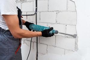 Man with demolition hammer remove stucco from wall. Renovation concept photo