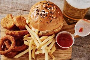 diferentes tipos de comida rápida y bocadillos y un vaso de cerveza en la mesa foto