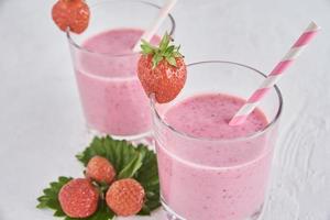 batido de fresa en vaso con paja y bayas frescas foto