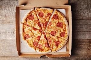 Slice of pizza in cardboard box, closeup photo