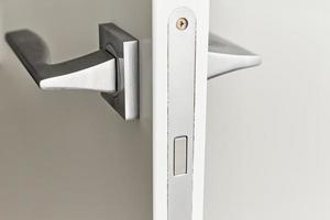 Silver door handle on a white door. Furniture accesories, interior element photo