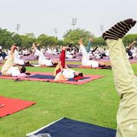 nueva delhi, india, 21 de junio de 2022 - sesión grupal de ejercicios de yoga para personas en el complejo deportivo yamuna en delhi el día internacional del yoga, gran grupo de adultos que asisten a clases de yoga en el estadio de cricket foto