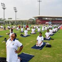 New Delhi, India, June 21 2022 - Group Yoga exercise session for people at Yamuna Sports Complex in Delhi on International Yoga Day, Big group of adults attending yoga class in cricket stadium photo