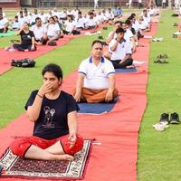 New Delhi, India, June 21 2022 - Group Yoga exercise session for people at Yamuna Sports Complex in Delhi on International Yoga Day, Big group of adults attending yoga class in cricket stadium photo