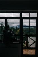 Silhouette of a woman sitting on the windowsill with a mug photo