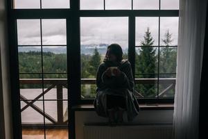 Silhouette of a woman sitting on the windowsill with a mug photo