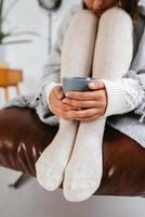 Cropped shot of woman sitting holding a mug at feet photo