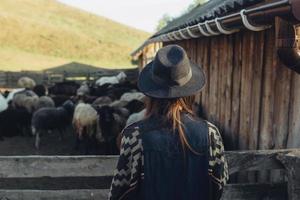 una mujer joven y hermosa cerca de un corral con cabras foto